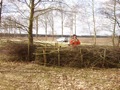 Een wandelsluis van wilgetakken precies op de grens, Bert staat in Nederland, ik in Belgi.