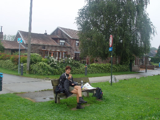 Nu werd het echt tijd voor de lunch. Bij gebrek aan bushokjes in de Walen op een natte bank gaan zitten. Bert doet uit protest haar poncho aan.